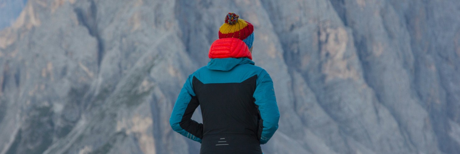 rigofree | professionelle Coachings Outdoor in den Dolomiten Südtirols zu jeder Jahreszeit und zu fast jedem Wetter Das Bild zeigt Paul Felix Rigo beim Betrachten der wunderbaren Dolomitenfelsen. Er trägt wärmende und sportliche Kleidung, weil es am Berg und in der Höhe nicht gerade warm ist.