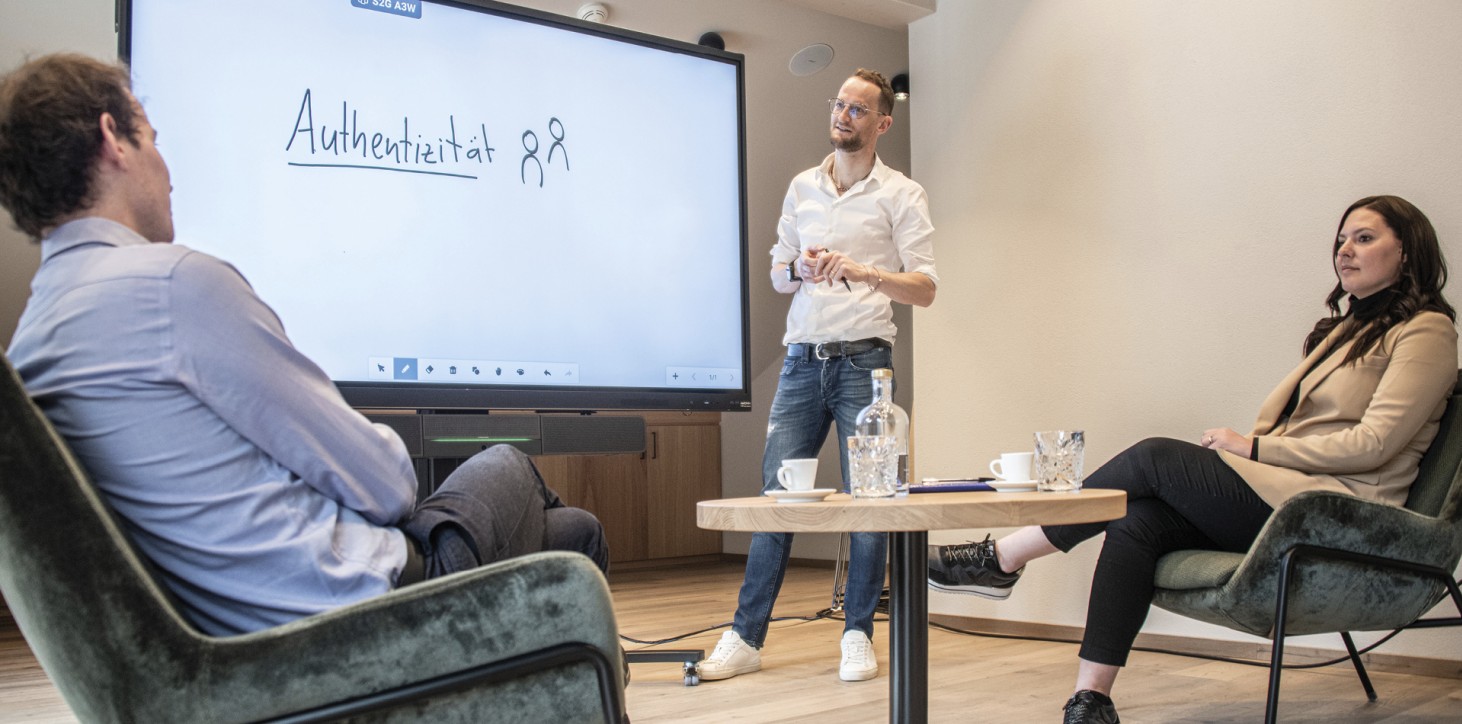 rigofree | professionelles Business Coaching für Leadership und Teams in Seminarräumen von Hotels oder in Deinem Unternehmen Das Bild zeigt Paul beim Coaching einer kleinen Gruppe in einem Seminarraum. Das Wort