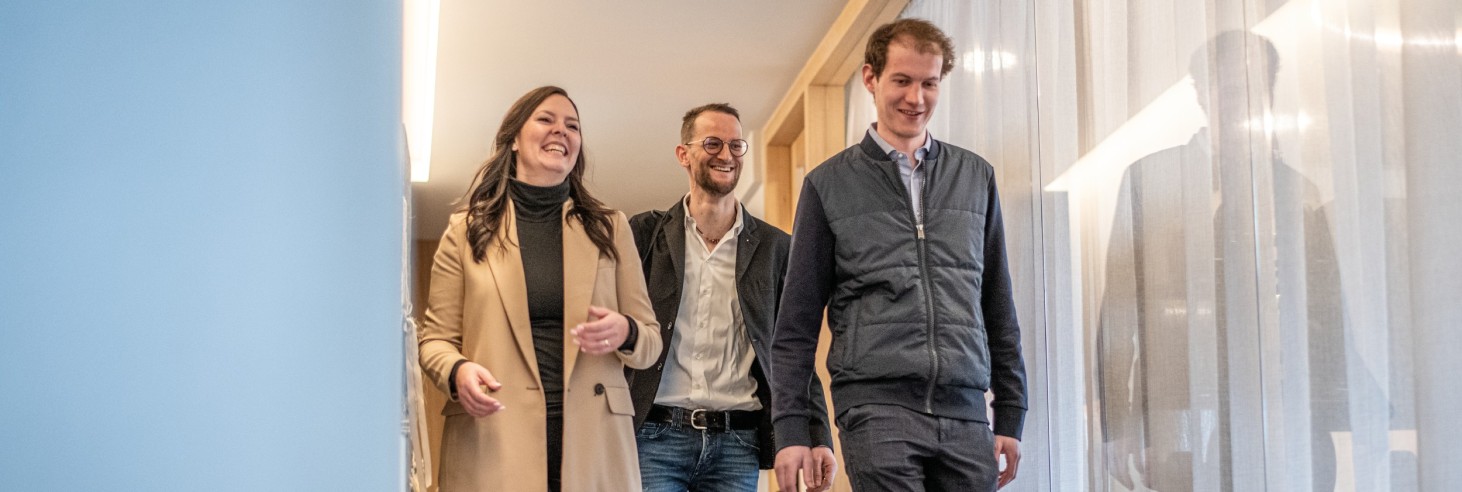 Das Bild zeigt ein lächelndes Paar nach Beendigung des Coachings mit Paul. Paul begleitet die beiden noch hinaus und wird sich dann verabschieden.